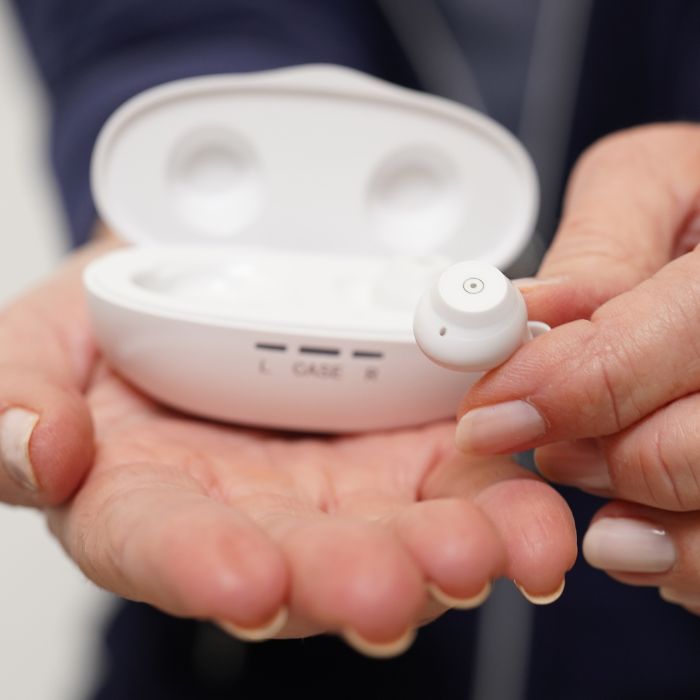 Fusion OTC hearing aids by Ceretone. Hand comparison of small device.