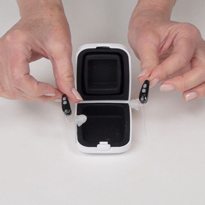 Ceretone over the counter hearing aids Nexus inside the case and on hand size comparison.